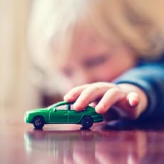 Enfant jouant avec une petite voiture verte